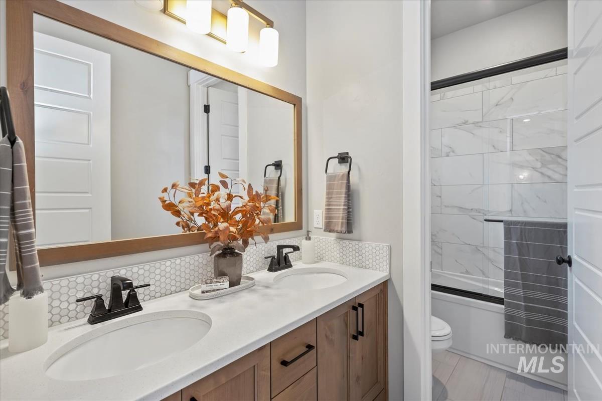 Bathroom featuring double vanity and bath / shower combo with glass door