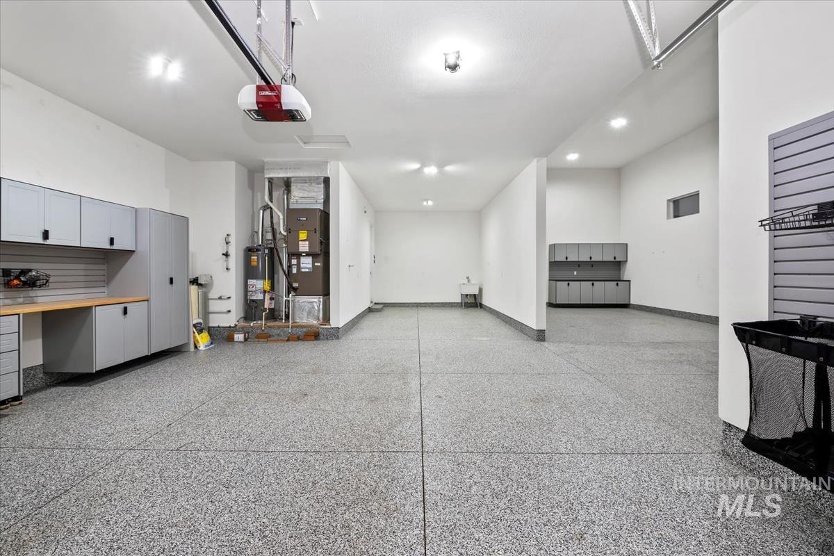 Garage with heating unit, gas water heater, a garage door opener, and recessed lighting
