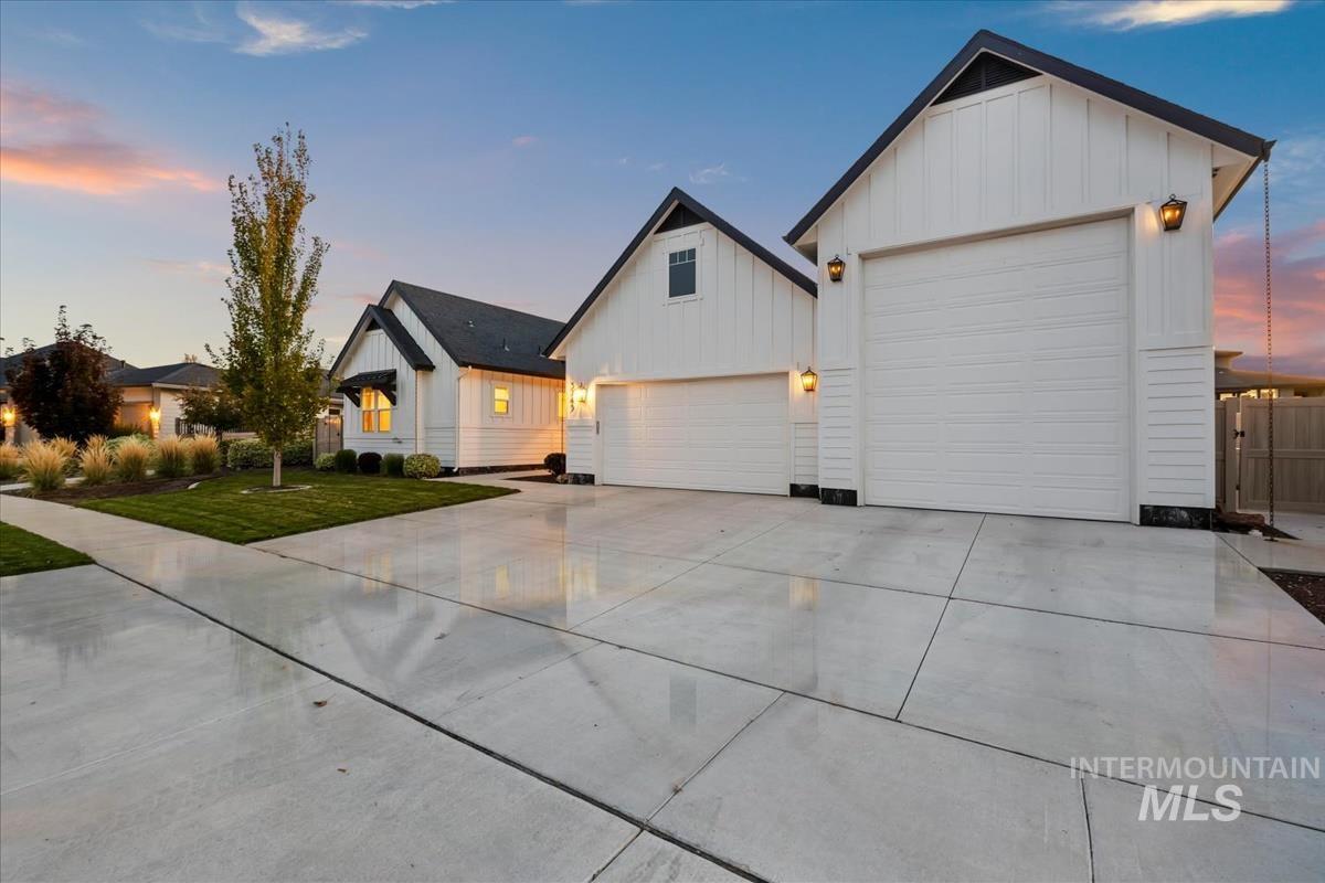 Modern farmhouse with board and batten siding, driveway, and a yard