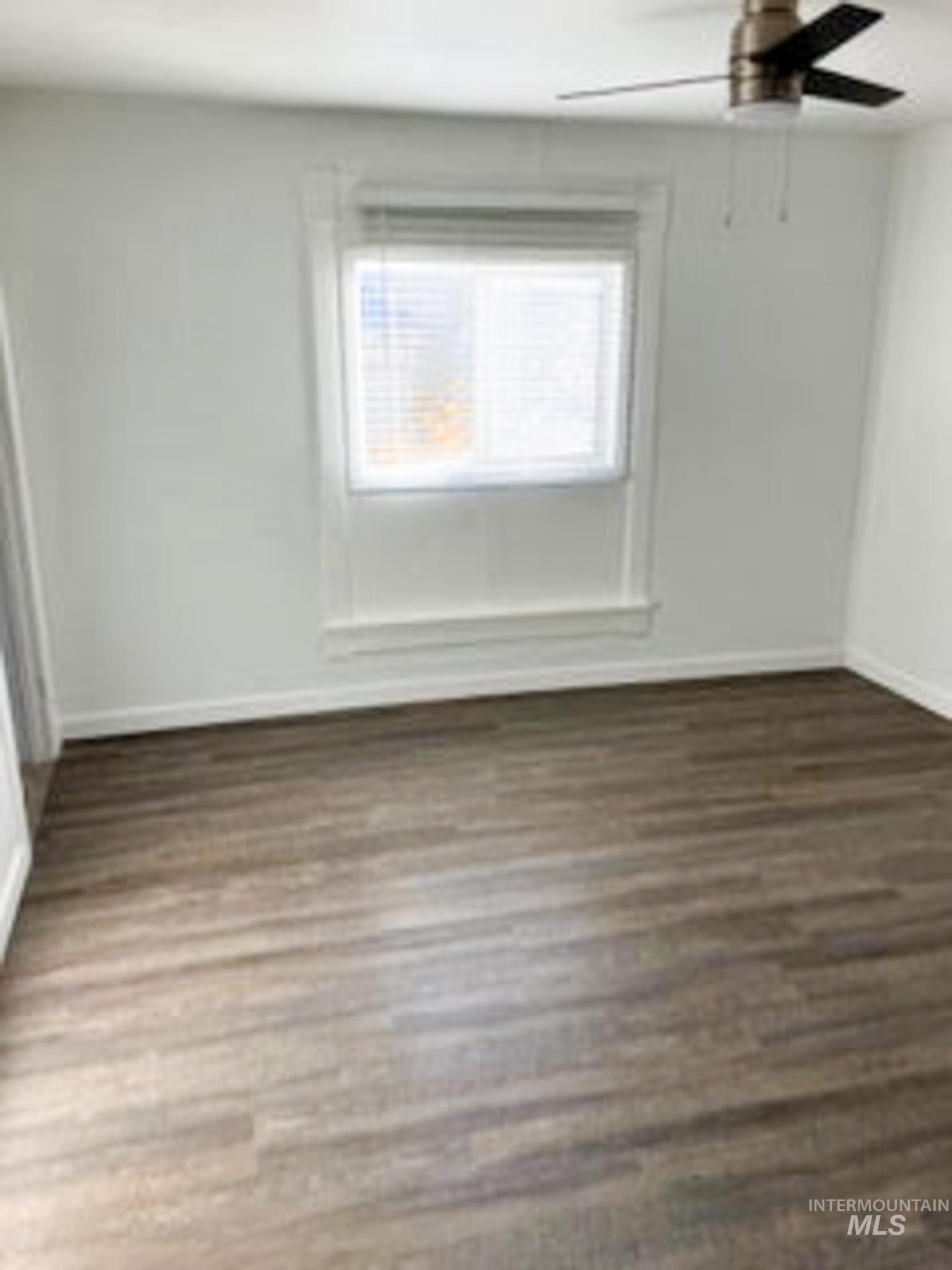 Unfurnished bedroom with dark wood-style floors and a ceiling fan