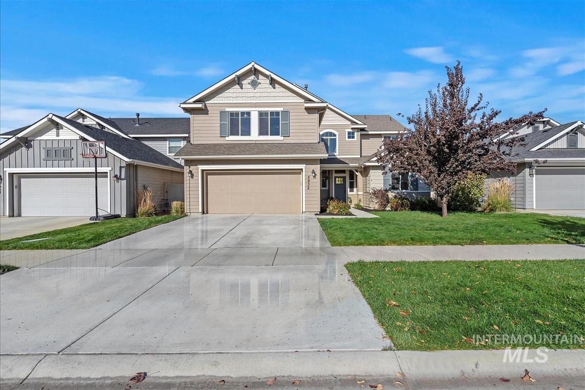 Craftsman-style home with a front yard, concrete driveway, a shingled roof, and an attached garage