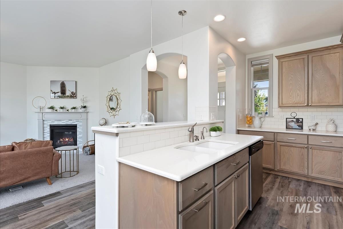Kitchen with backsplash, dark wood-type flooring, pendant lighting, open floor plan, and recessed lighting