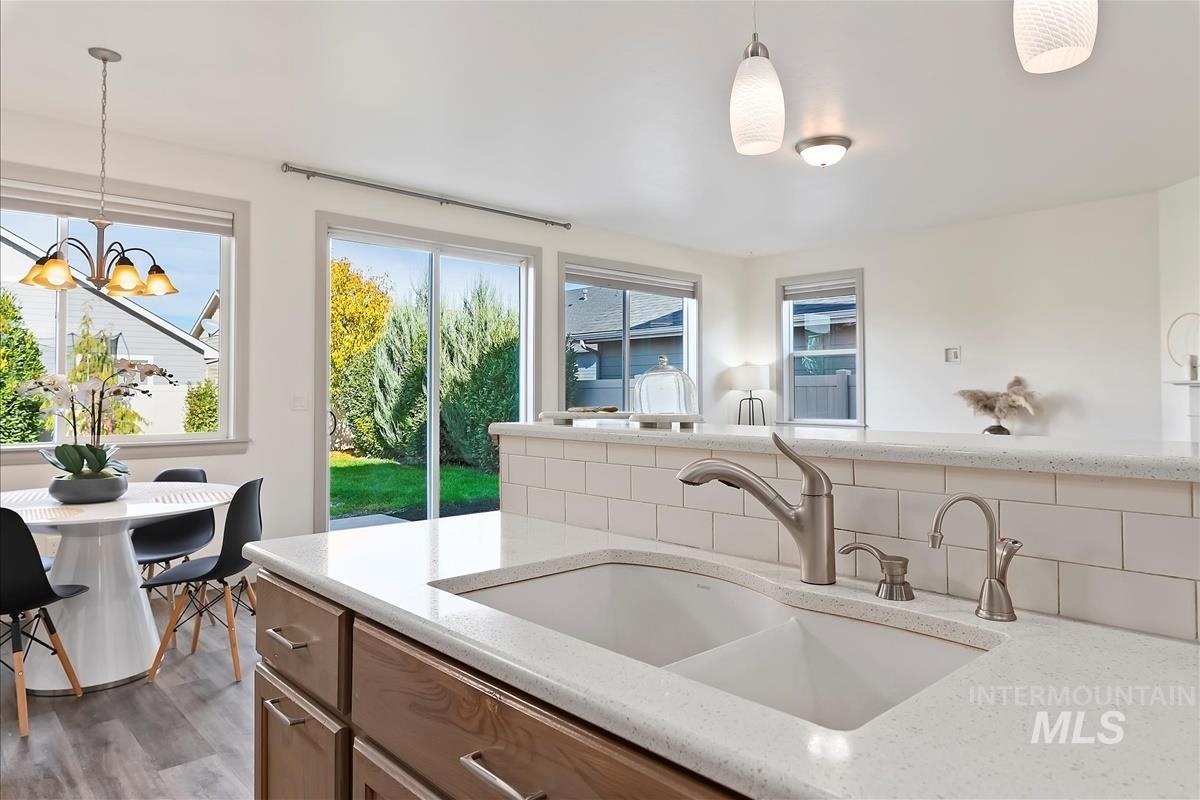 Kitchen featuring light stone counters, decorative light fixtures, backsplash, and a chandelier