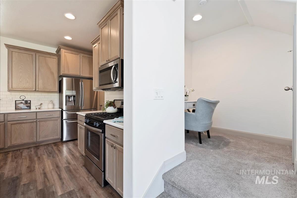 Kitchen featuring appliances with stainless steel finishes, backsplash, recessed lighting, and dark colored carpet