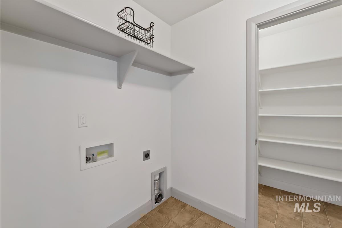 Laundry room featuring electric dryer hookup, light tile patterned floors, and washer hookup