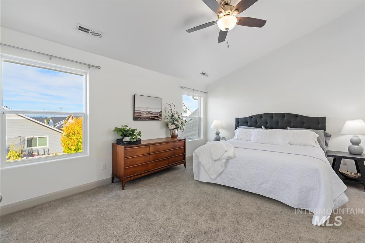 Carpeted bedroom with vaulted ceiling and a ceiling fan