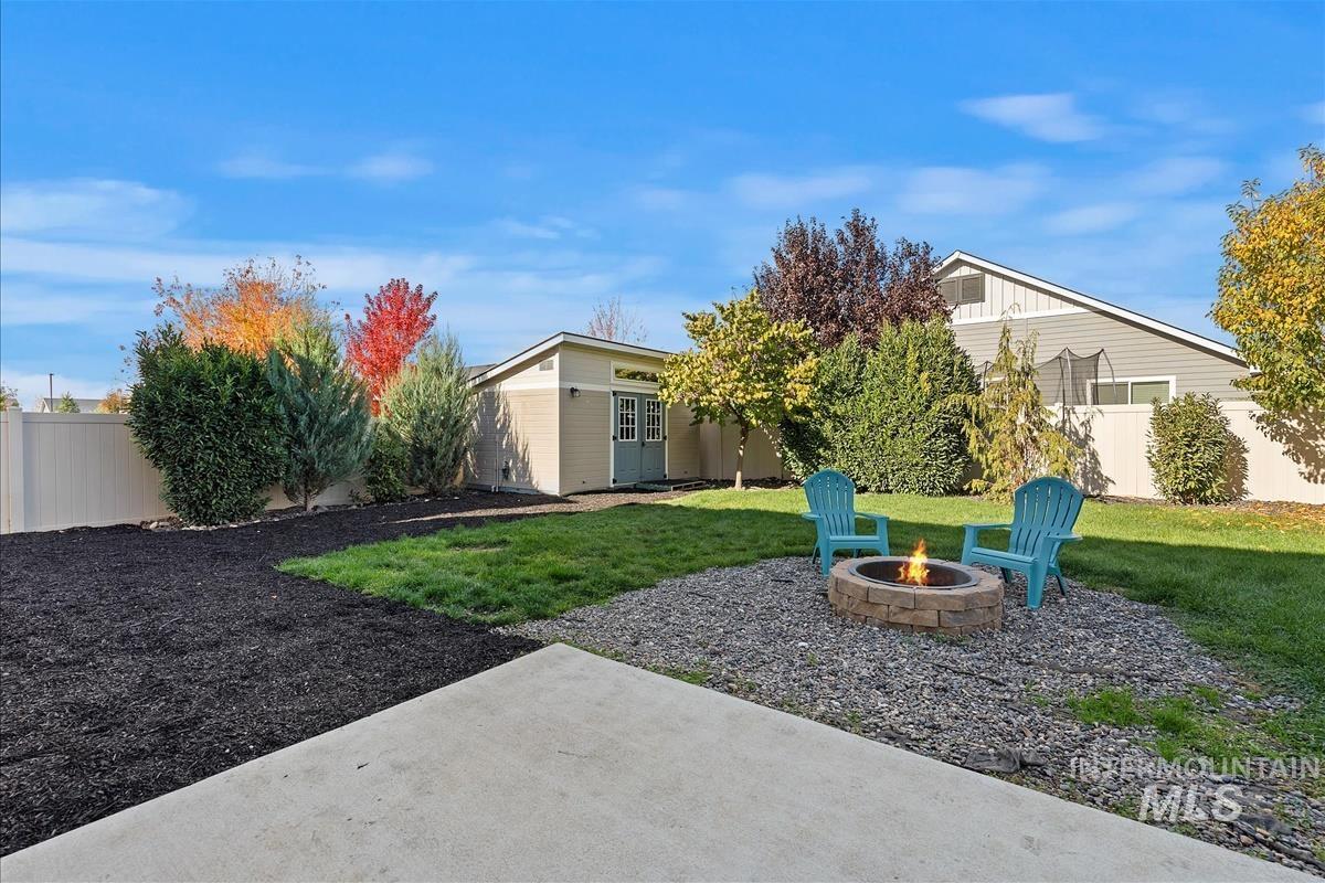 Fenced backyard with an outbuilding, an outdoor fire pit, and a patio