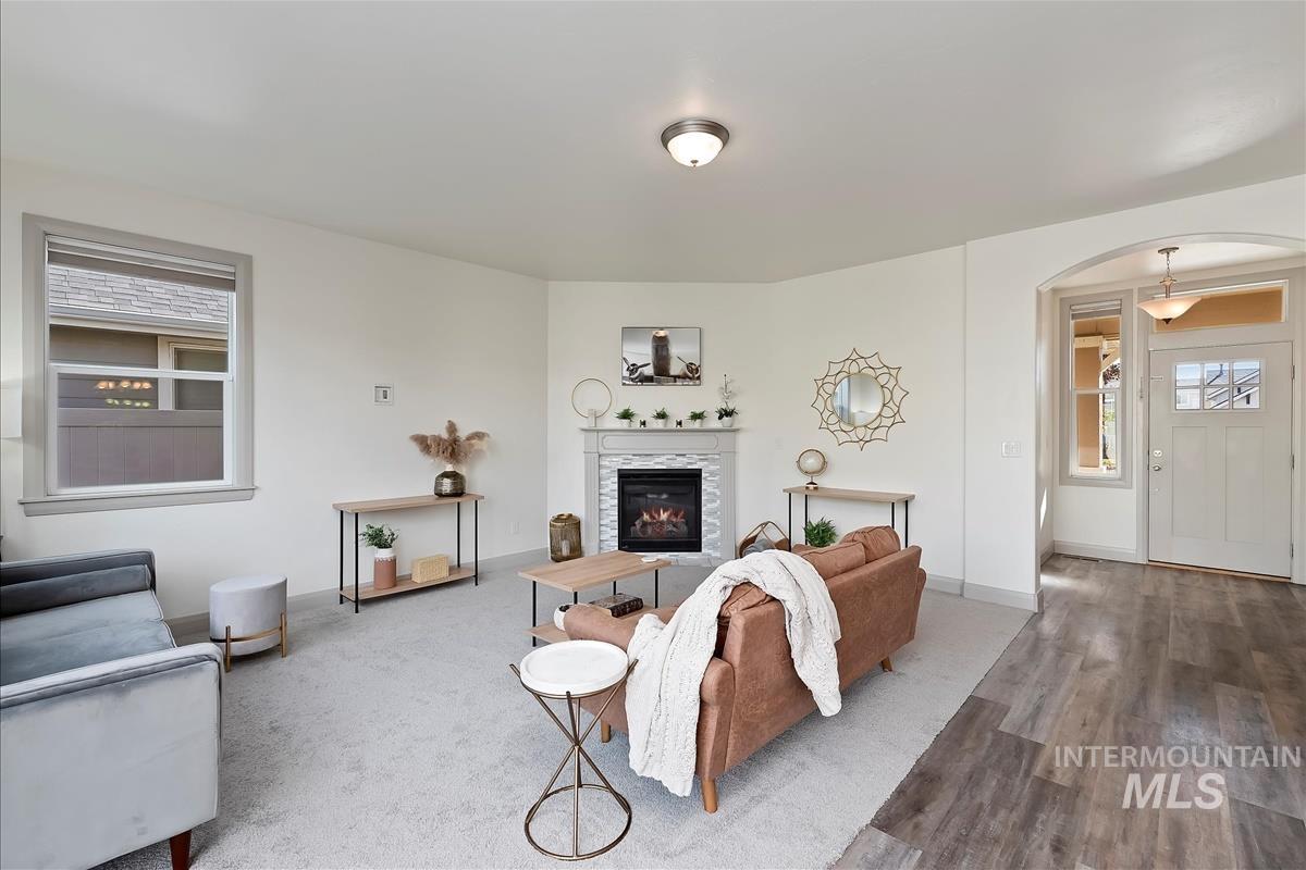 Living area with arched walkways, wood finished floors, and a tiled fireplace