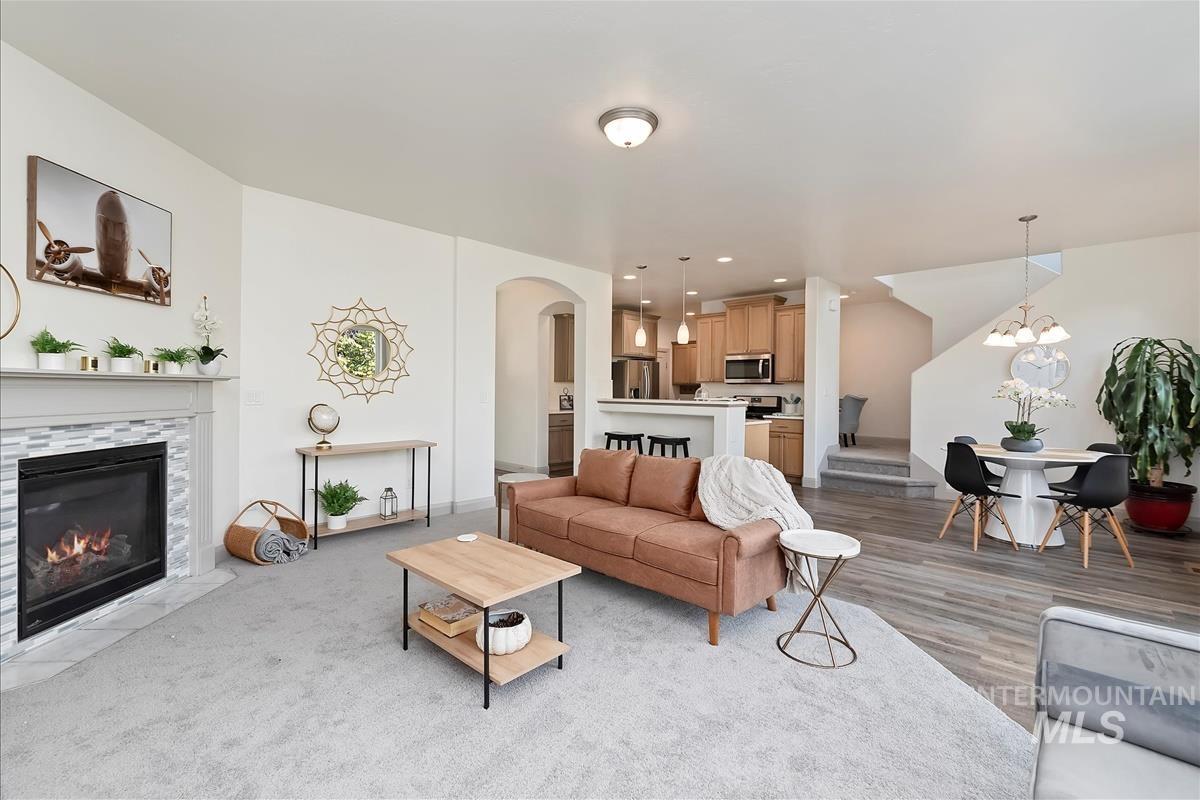 Living area with arched walkways, a tiled fireplace, a chandelier, recessed lighting, and light wood finished floors
