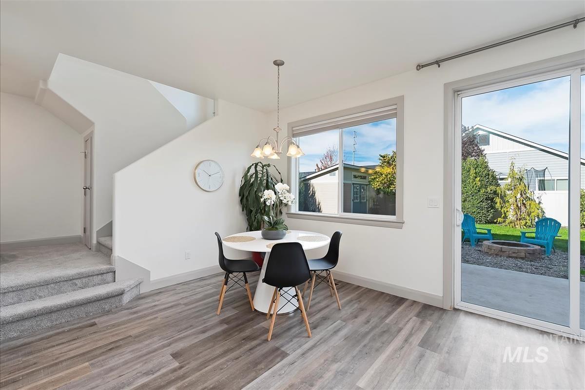 Dining room with plenty of natural light, a chandelier, stairs, and light wood-style flooring