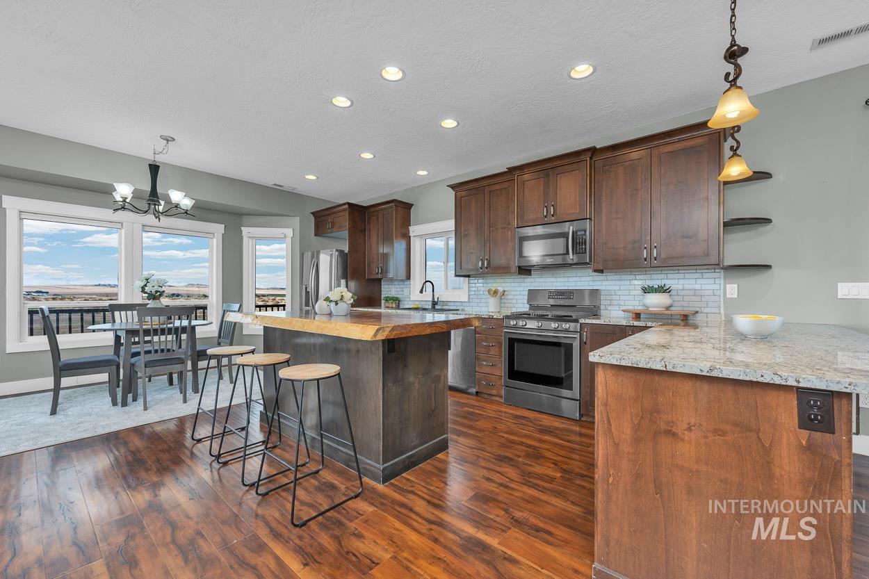 Kitchen featuring pendant lighting, a kitchen breakfast bar, open shelves, appliances with stainless steel finishes, and recessed lighting