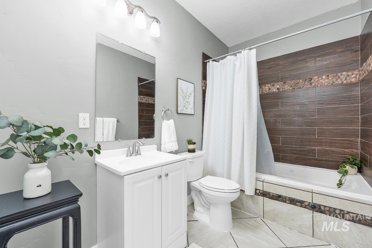 Bathroom featuring tiled shower / bath, vanity, and light tile patterned floors