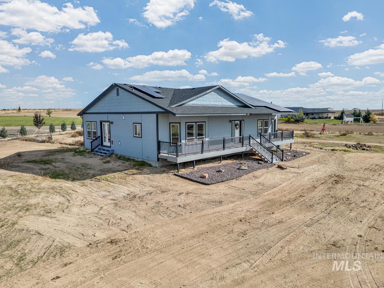 View of front of property with roof mounted solar panels, roof with shingles, a rural view, and covered porch