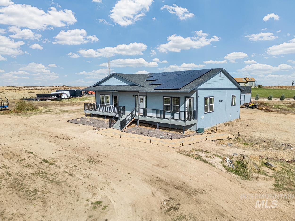 View of front of home with covered porch, solar panels, and a shingled roof