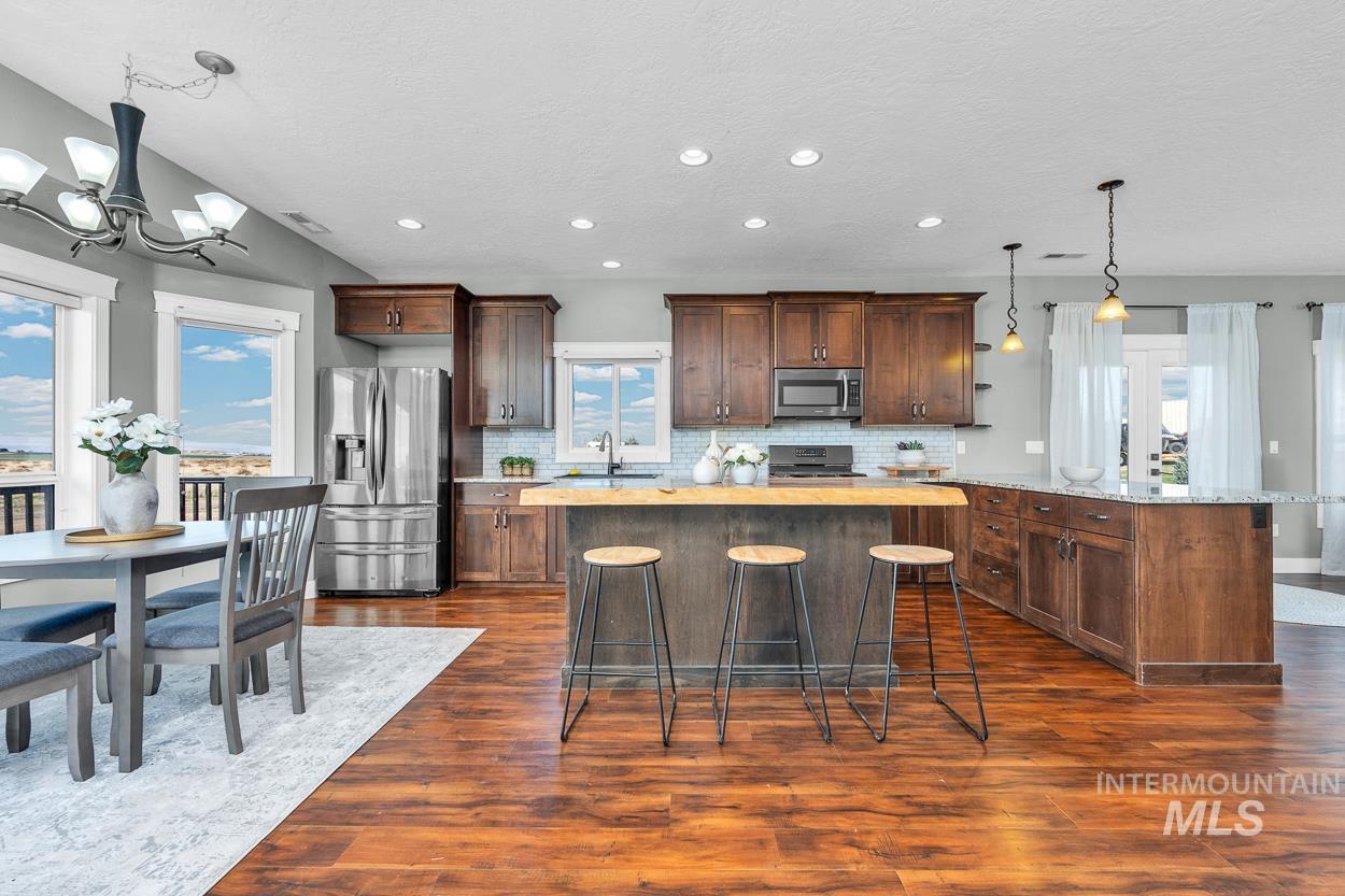 Kitchen featuring hanging light fixtures, a breakfast bar, decorative backsplash, appliances with stainless steel finishes, and recessed lighting