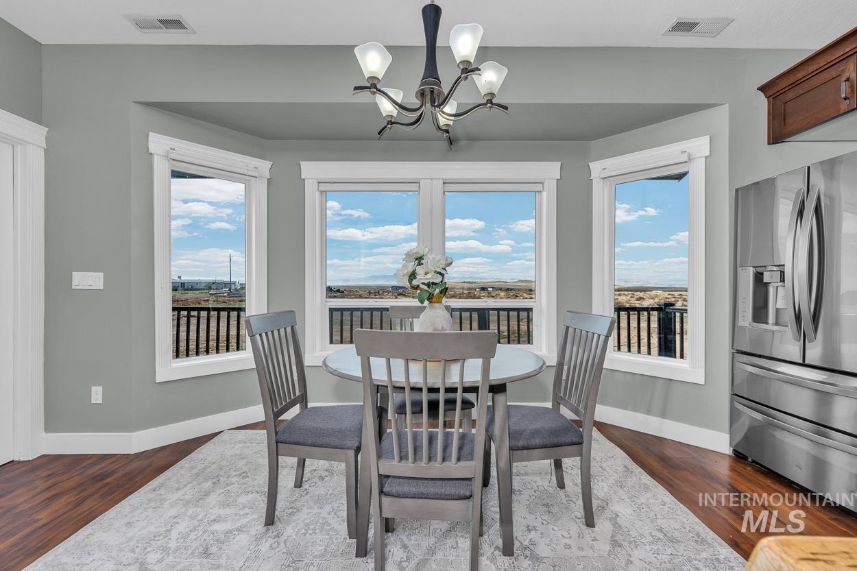 Dining area with a chandelier, healthy amount of natural light, and dark wood-style floors