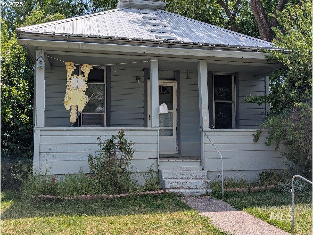View of front facade featuring a porch, a metal roof, and a front yard