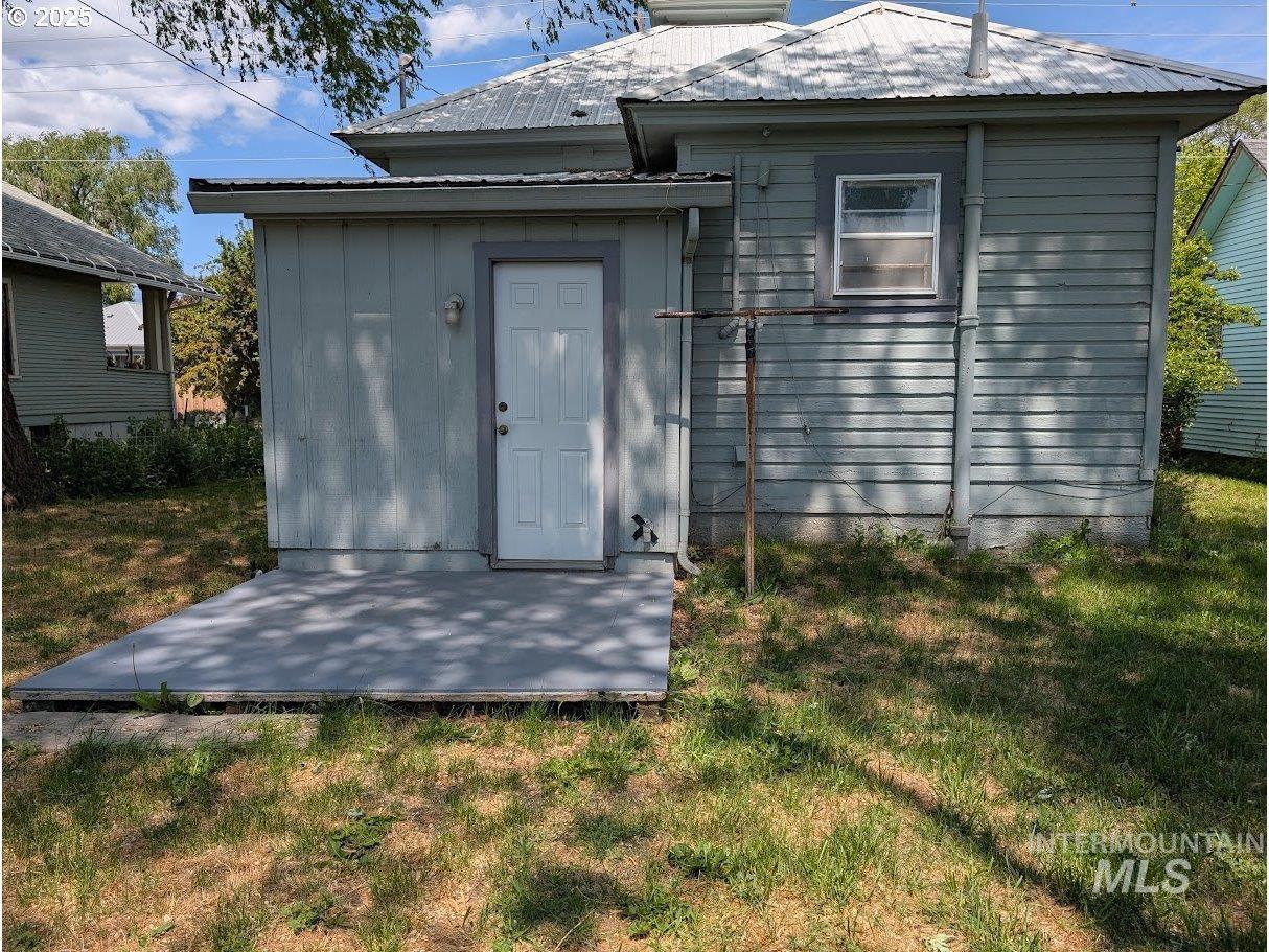 Back of house with a metal roof and a yard
