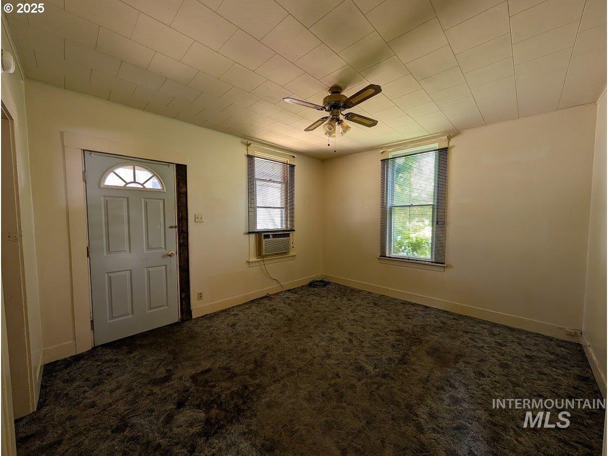 Foyer entrance with dark carpet, a ceiling fan, and cooling unit