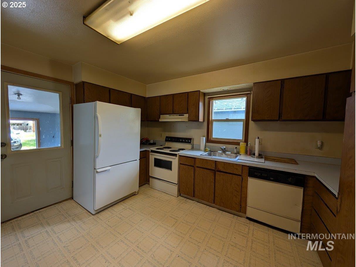 Kitchen featuring white appliances, light countertops, light flooring, and under cabinet range hood