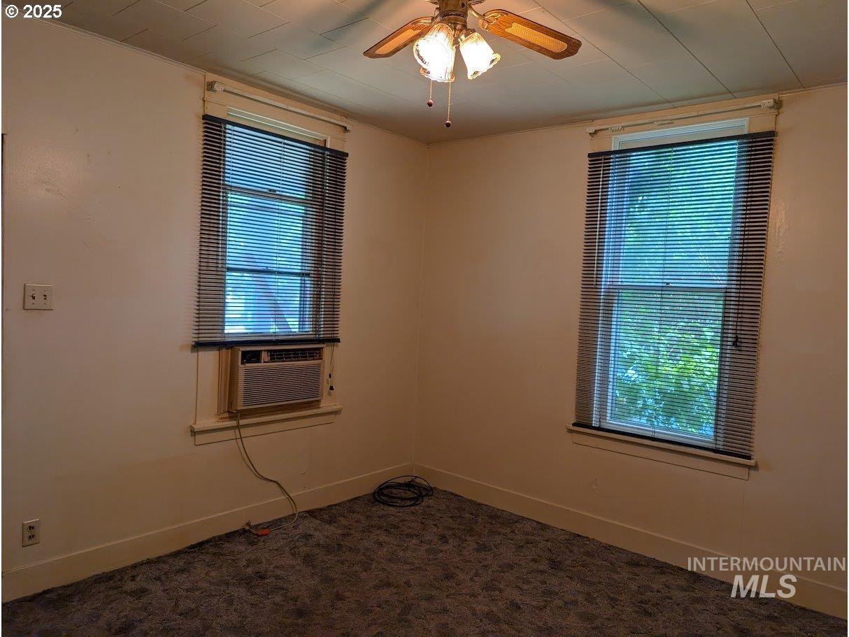 Unfurnished room featuring dark colored carpet, ceiling fan, and cooling unit