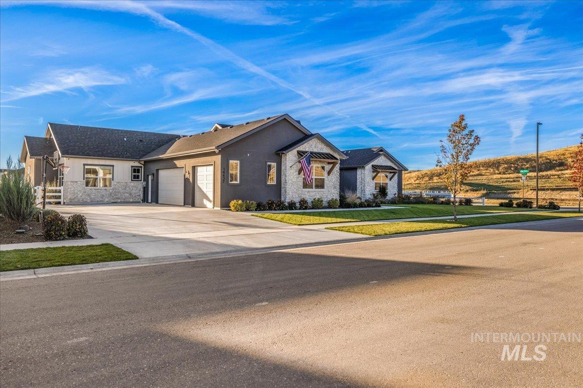 View of front of house featuring stone siding, concrete driveway, stucco siding, a garage, and a front yard