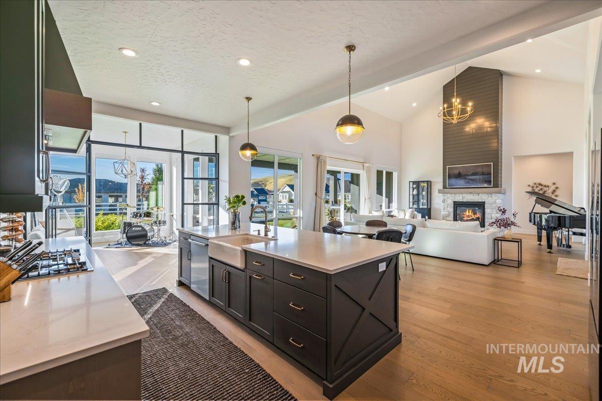 Kitchen featuring a fireplace, a chandelier, hanging light fixtures, open floor plan, and high vaulted ceiling