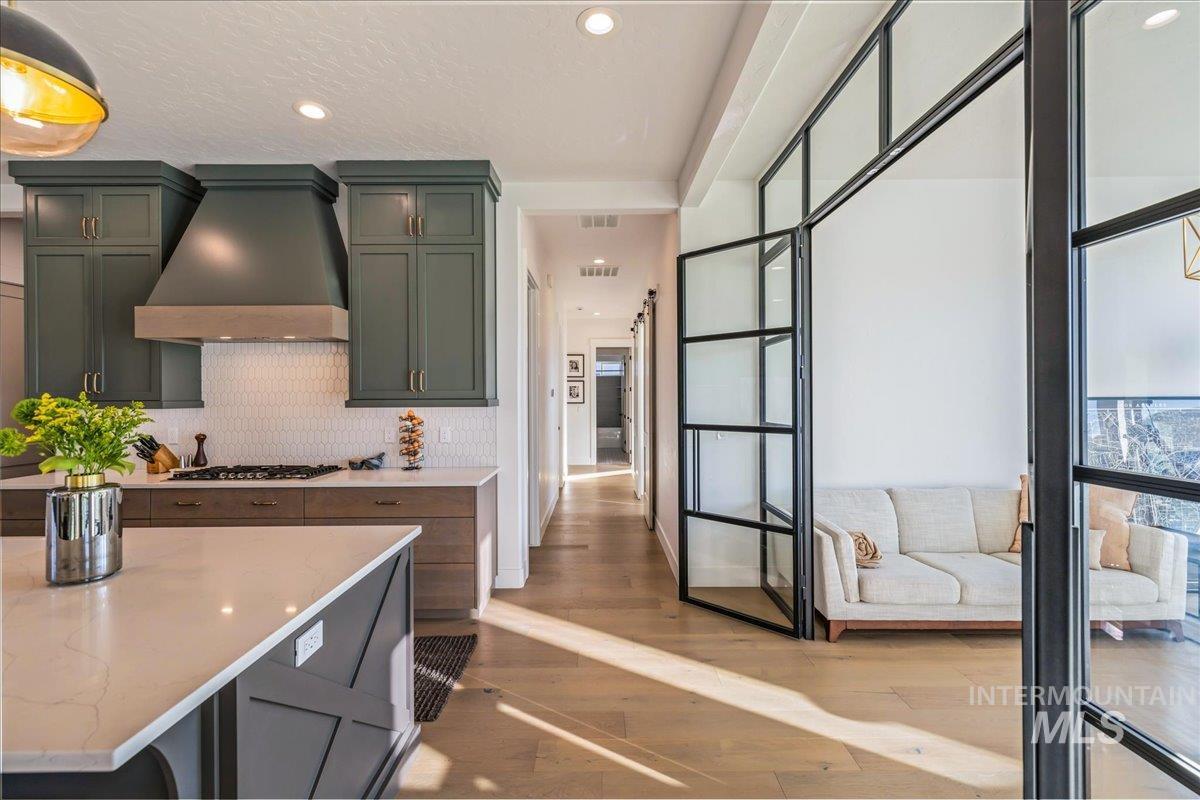 Kitchen featuring custom exhaust hood, light wood-type flooring, light stone counters, recessed lighting, and green cabinets