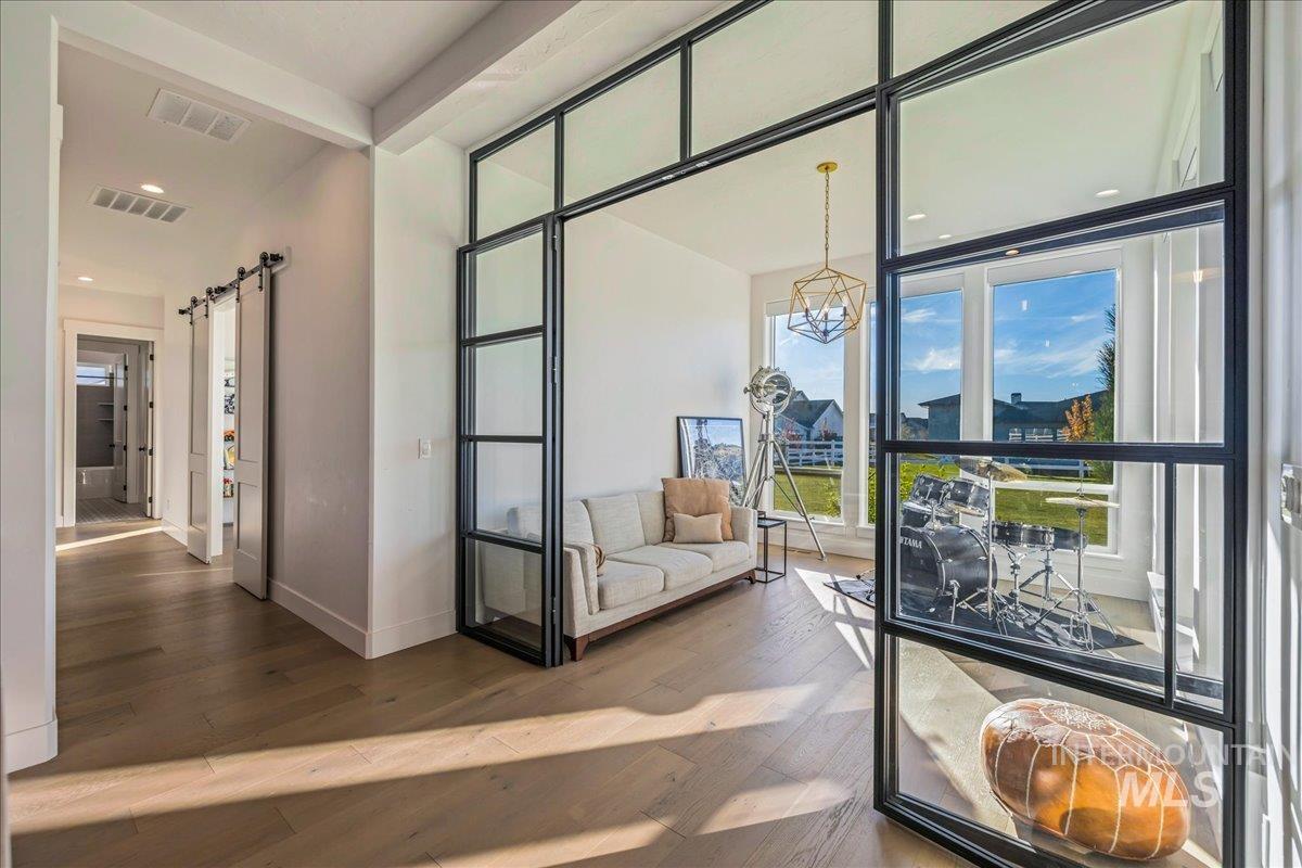 Interior space featuring a barn door, wood-type flooring, floor to ceiling windows, recessed lighting, and a chandelier