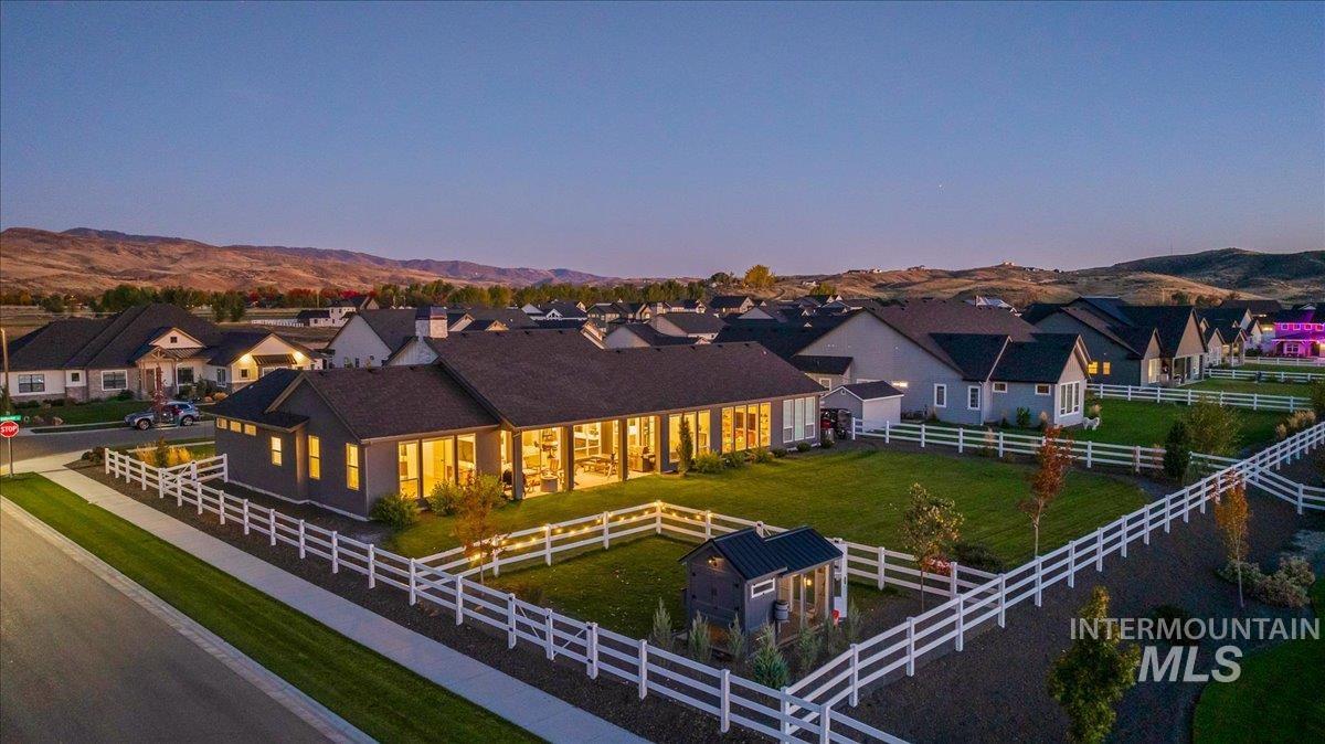 Back of house at dusk with a residential view, a mountain view, a fenced backyard, and a patio area