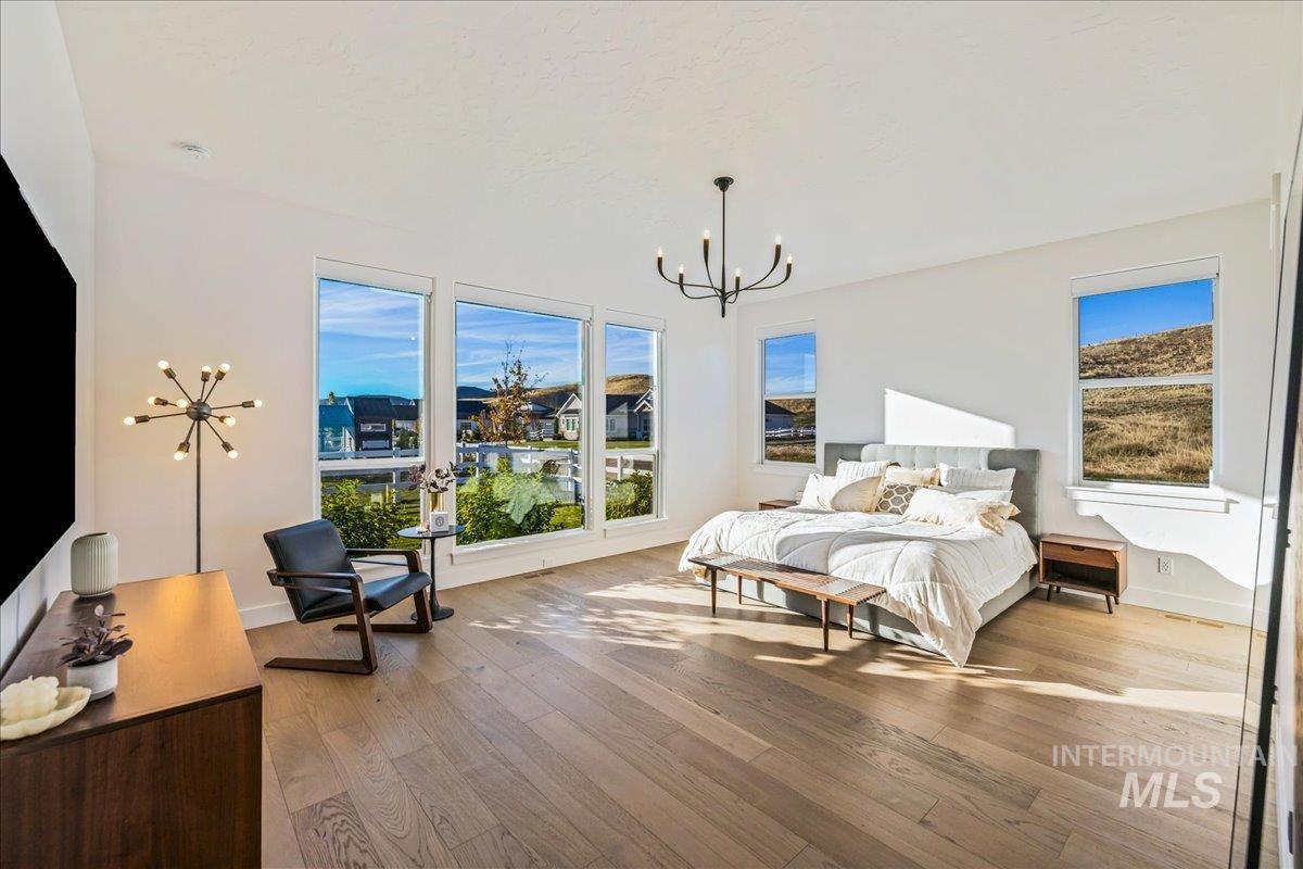 Bedroom with light wood finished floors, multiple windows, and a chandelier