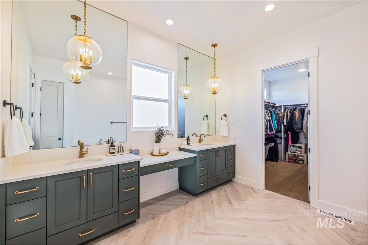 Bathroom with double vanity, recessed lighting, a chandelier, a walk in closet, and parquet flooring