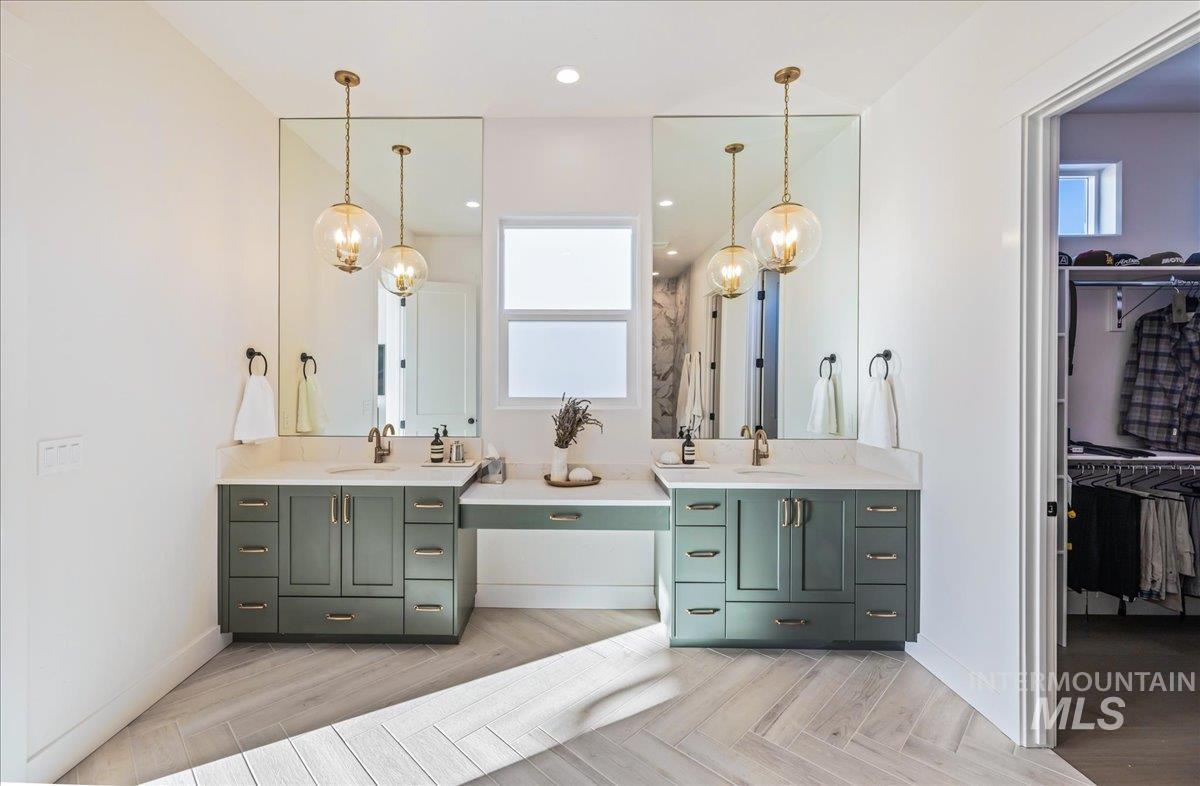 Full bathroom with healthy amount of natural light, a chandelier, two vanities, a walk in closet, and recessed lighting
