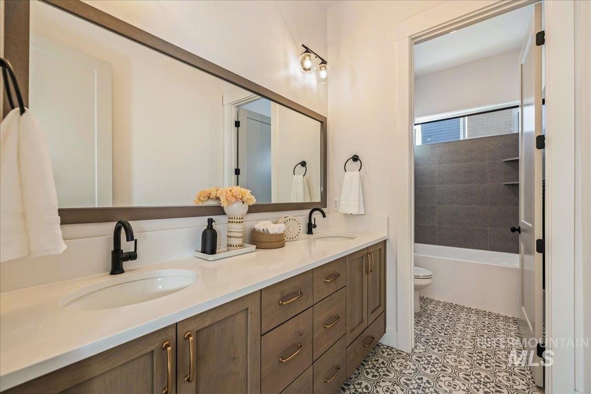 Bathroom featuring double vanity,  shower combination, and light tile patterned flooring