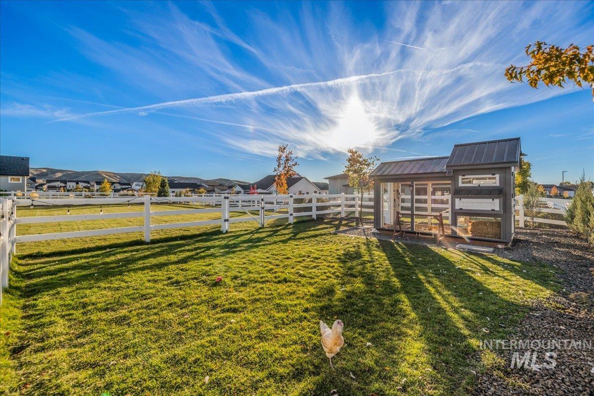 Fenced backyard featuring exterior structure, a residential view, and an outbuilding