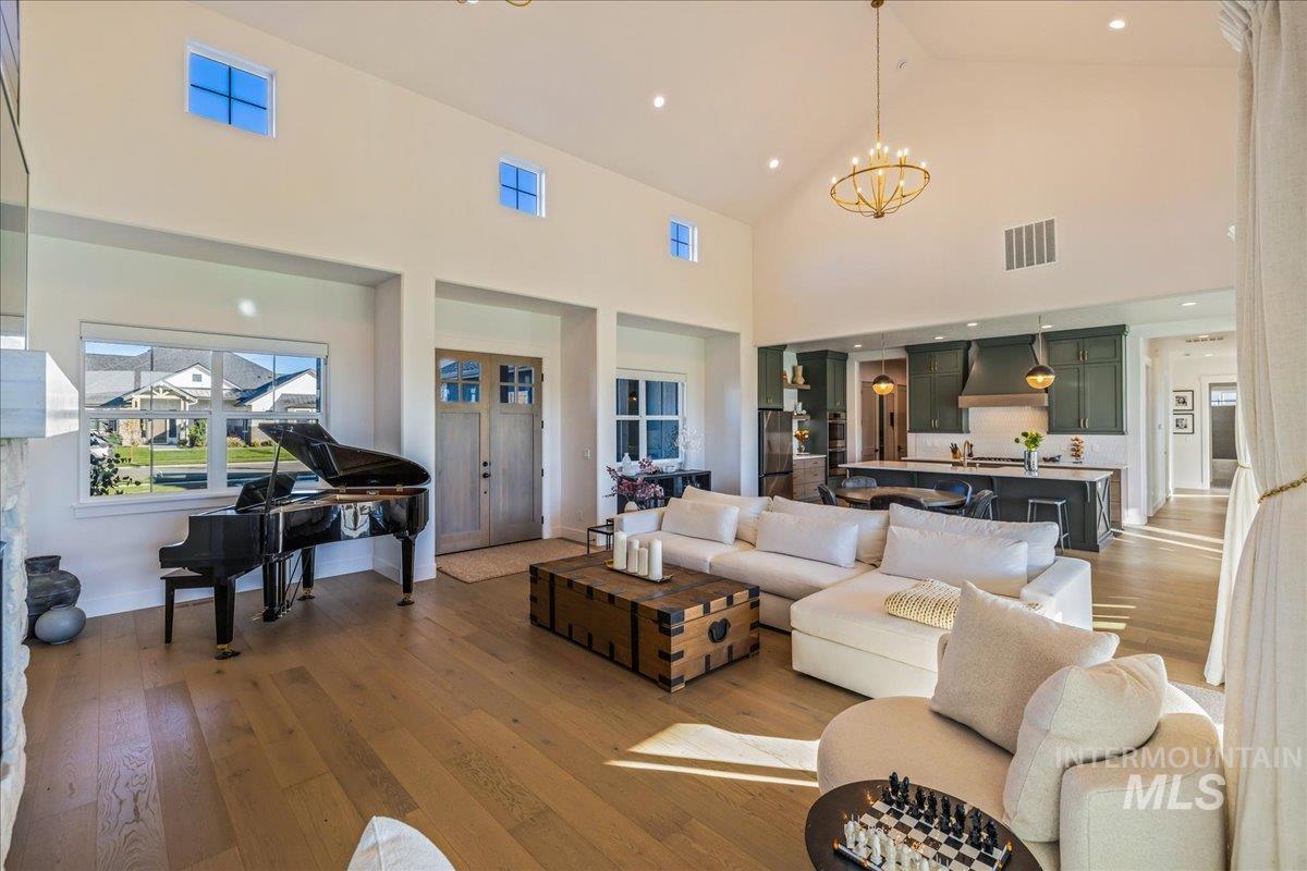 Living area featuring light wood-style flooring, high vaulted ceiling, recessed lighting, and a chandelier