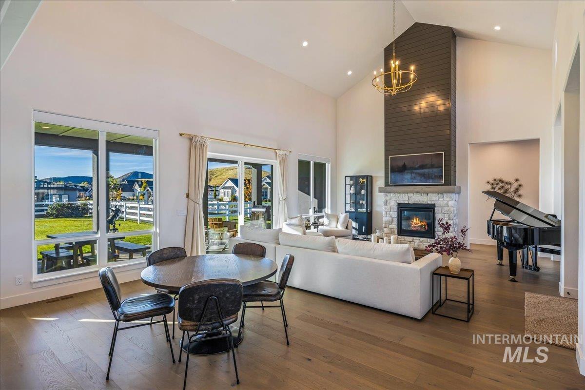 Dining room with high vaulted ceiling, a fireplace, hardwood / wood-style floors, and a chandelier