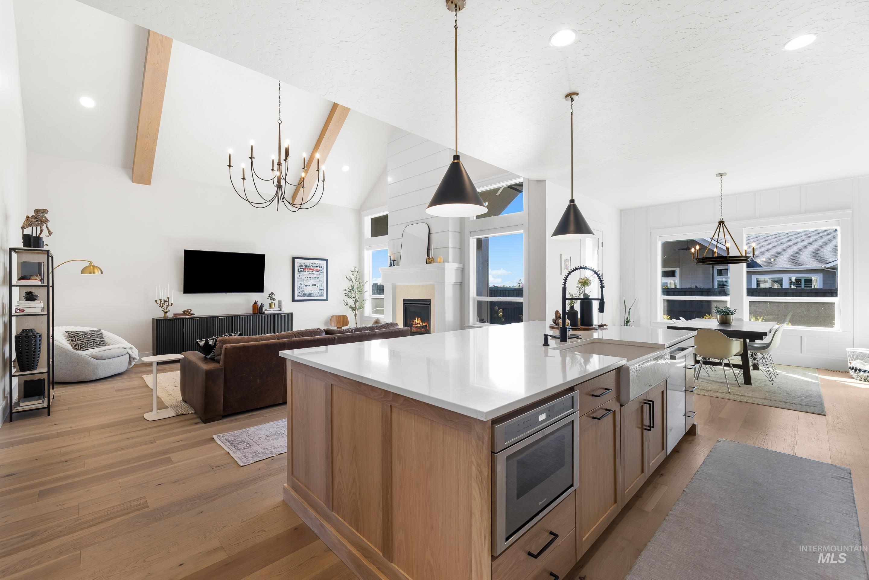 Kitchen with a chandelier, recessed lighting, light wood-style flooring, a warm lit fireplace, and open floor plan