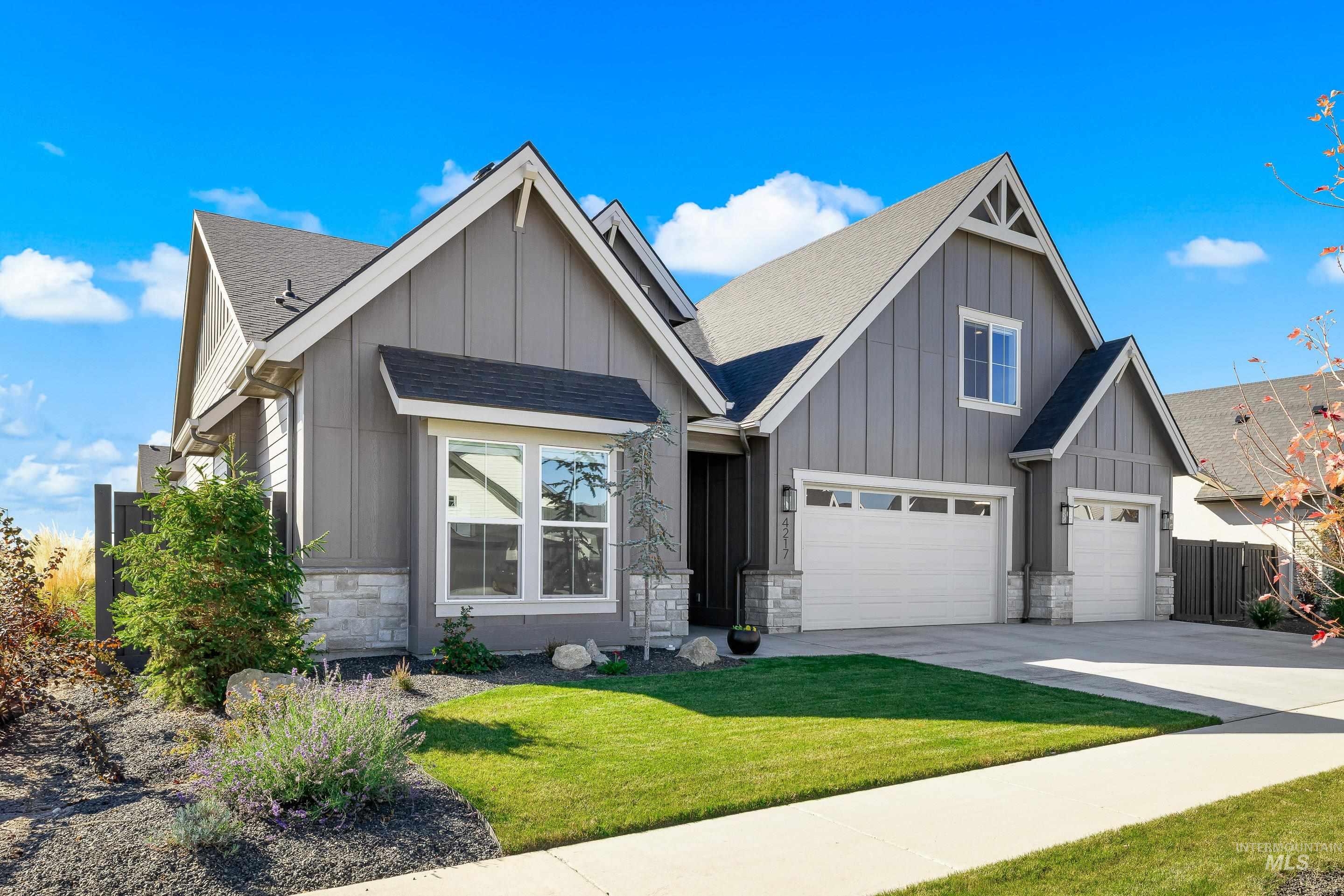 View of front facade featuring board and batten siding, a shingled roof, stone siding, and concrete driveway