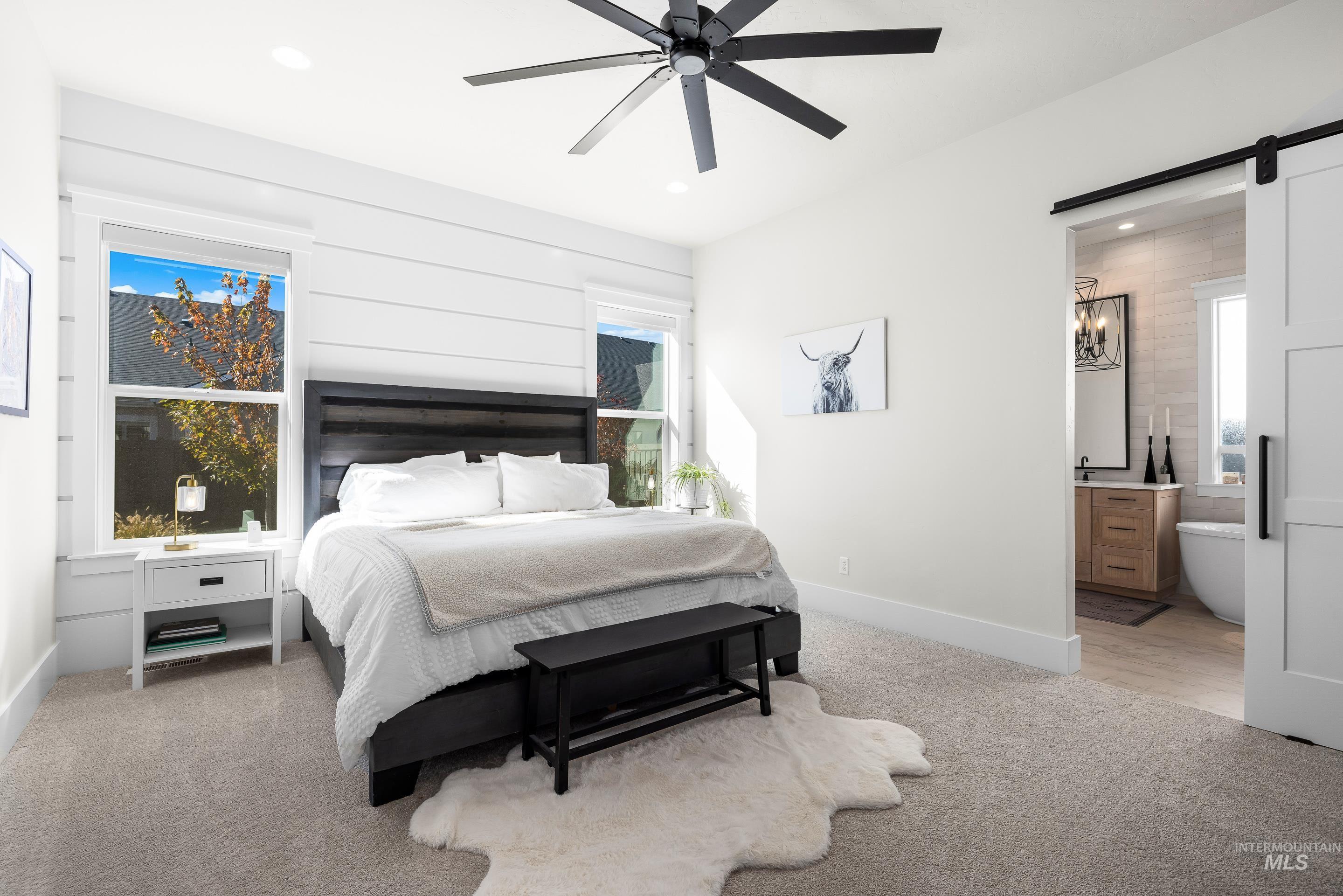 Bedroom with a barn door, light colored carpet, ceiling fan, connected bathroom, and recessed lighting