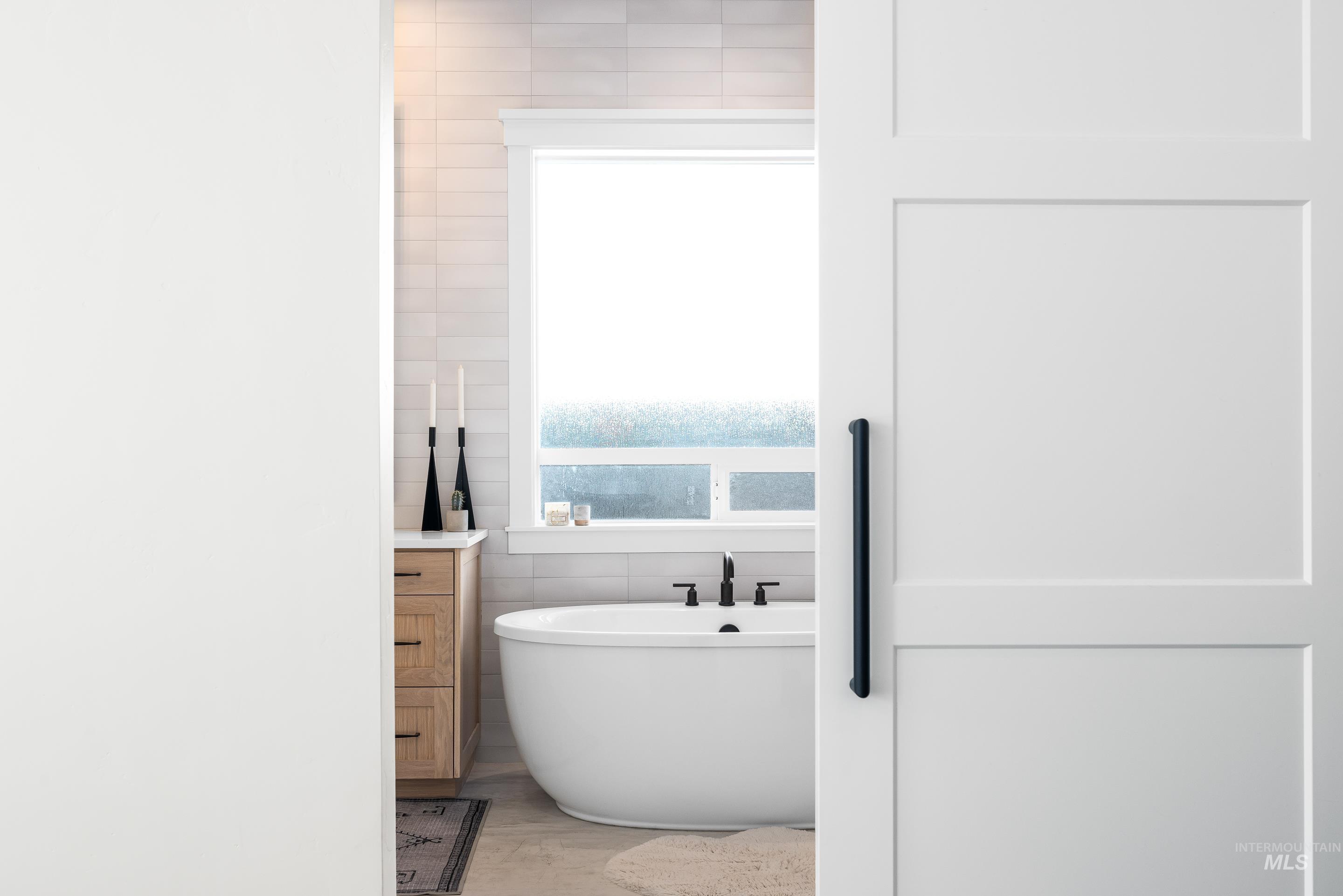 Full bathroom with a soaking tub, tile walls, and light wood-style floors
