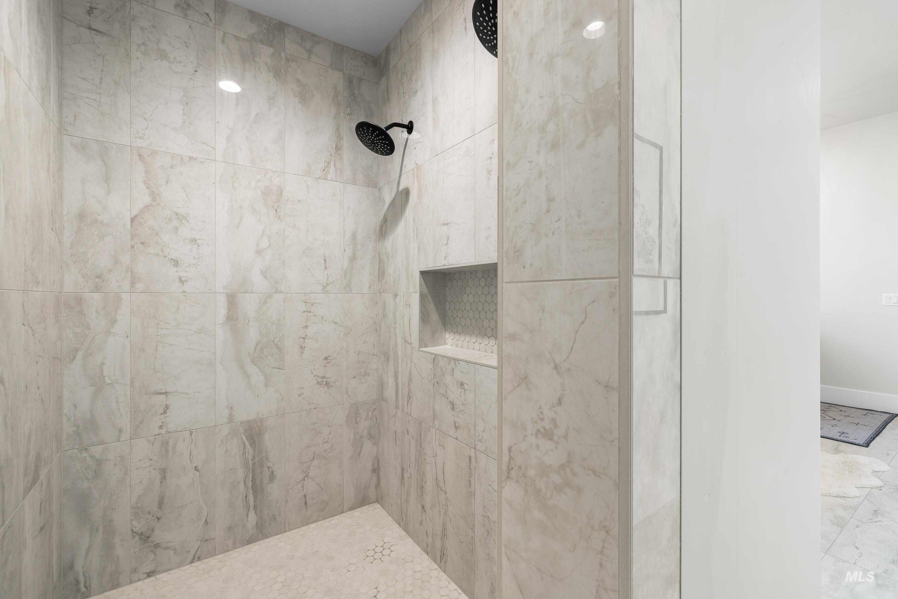 Bathroom featuring tiled shower and baseboards