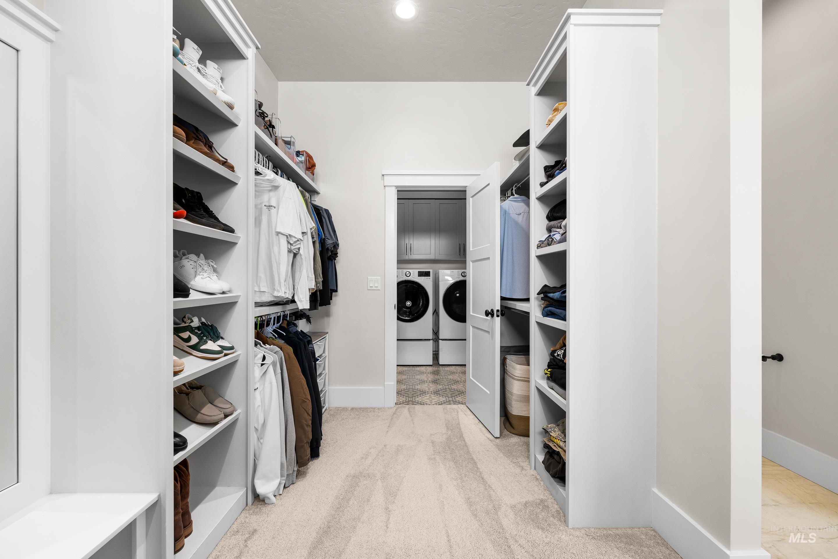 Spacious closet featuring light carpet, washing machine and clothes dryer, and water heater