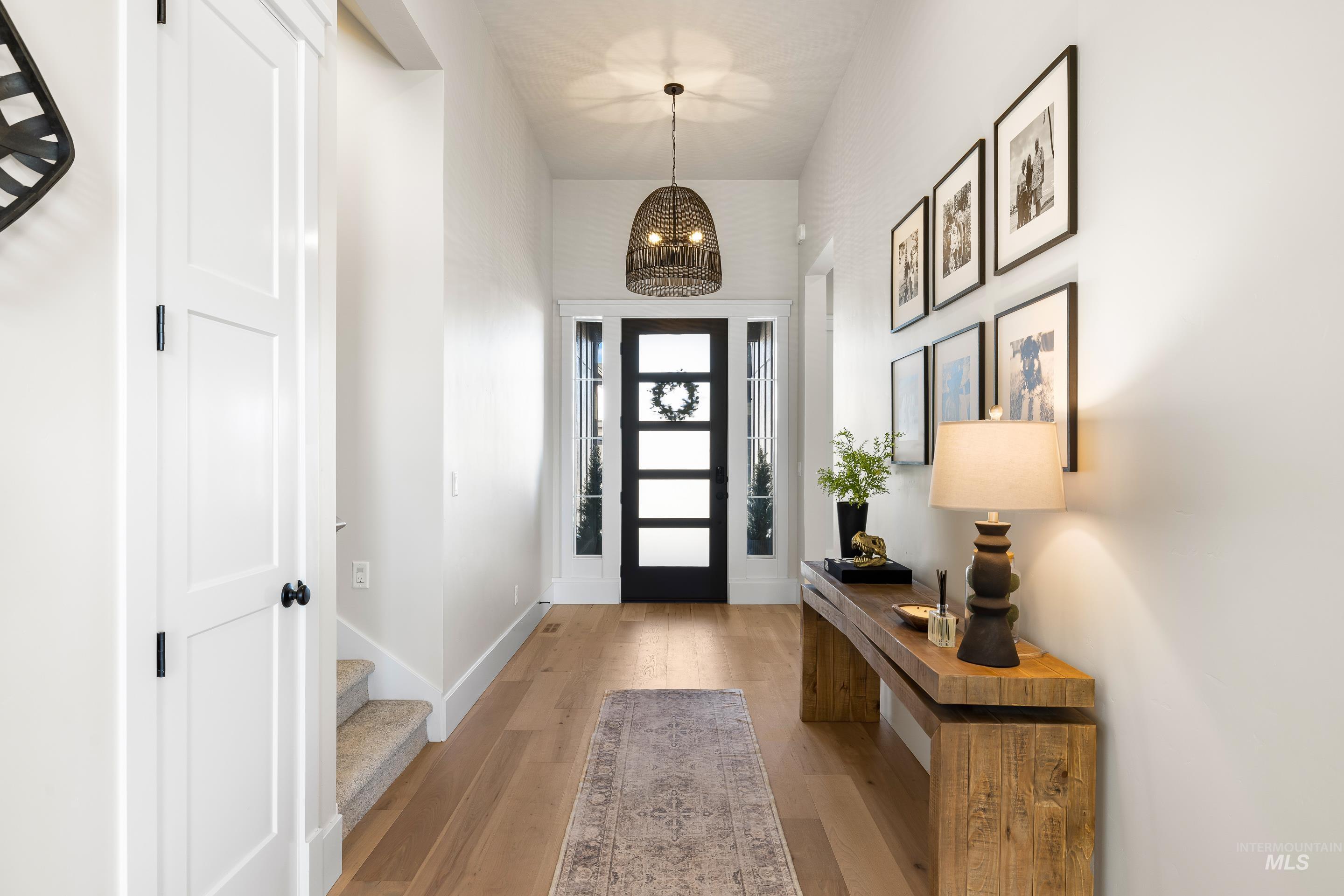 Entryway featuring light wood-style floors, a chandelier, stairs, and a towering ceiling