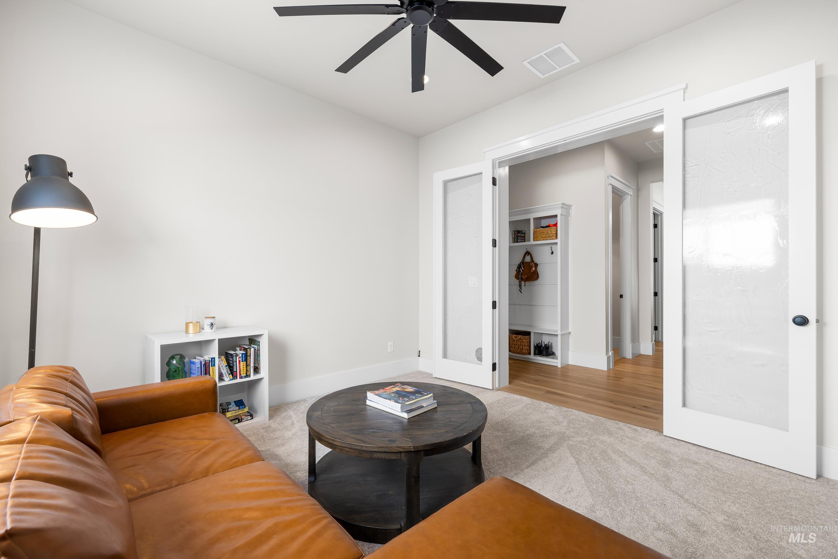 Living area featuring light colored carpet and ceiling fan