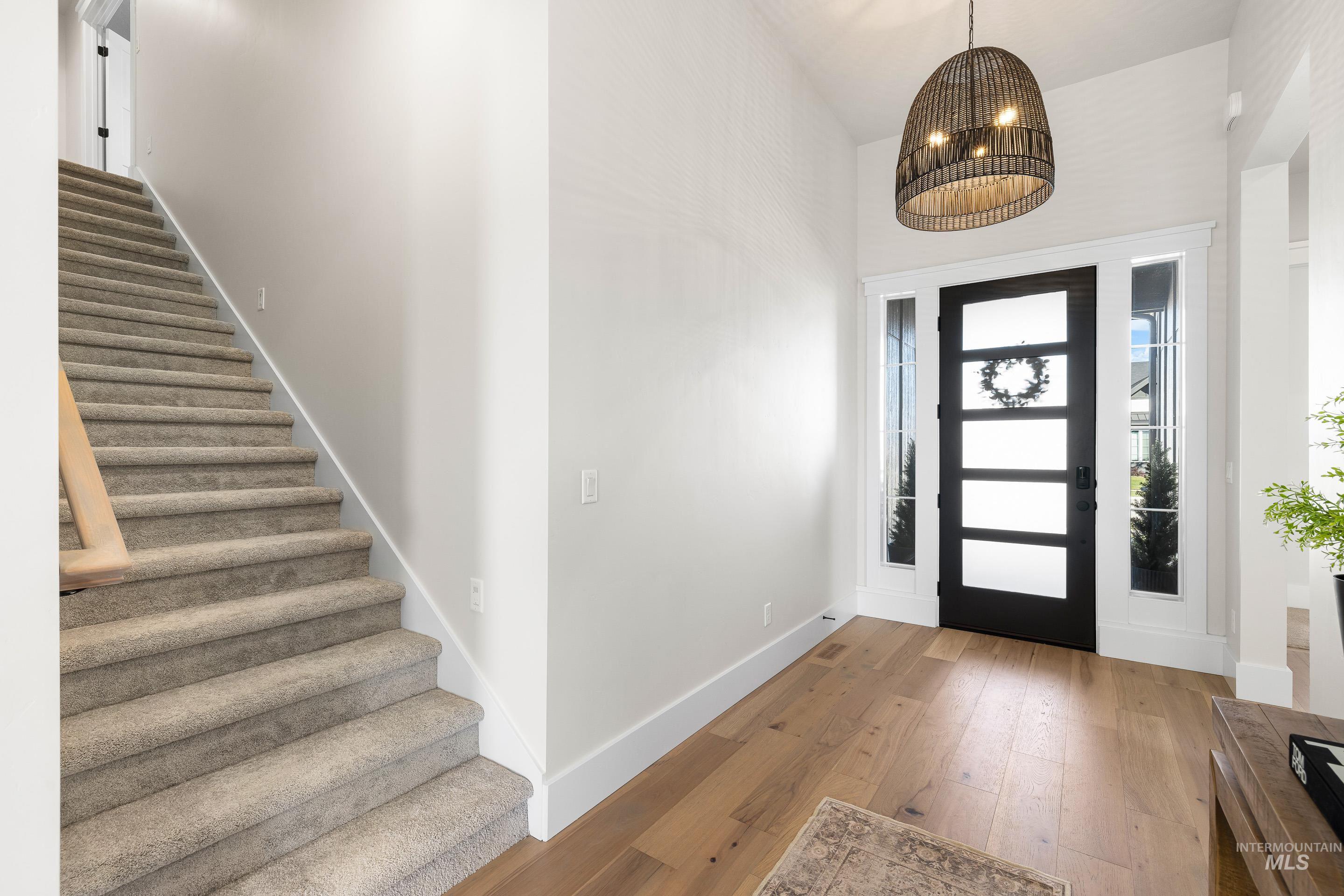Foyer featuring hardwood / wood-style floors, stairway, and a chandelier