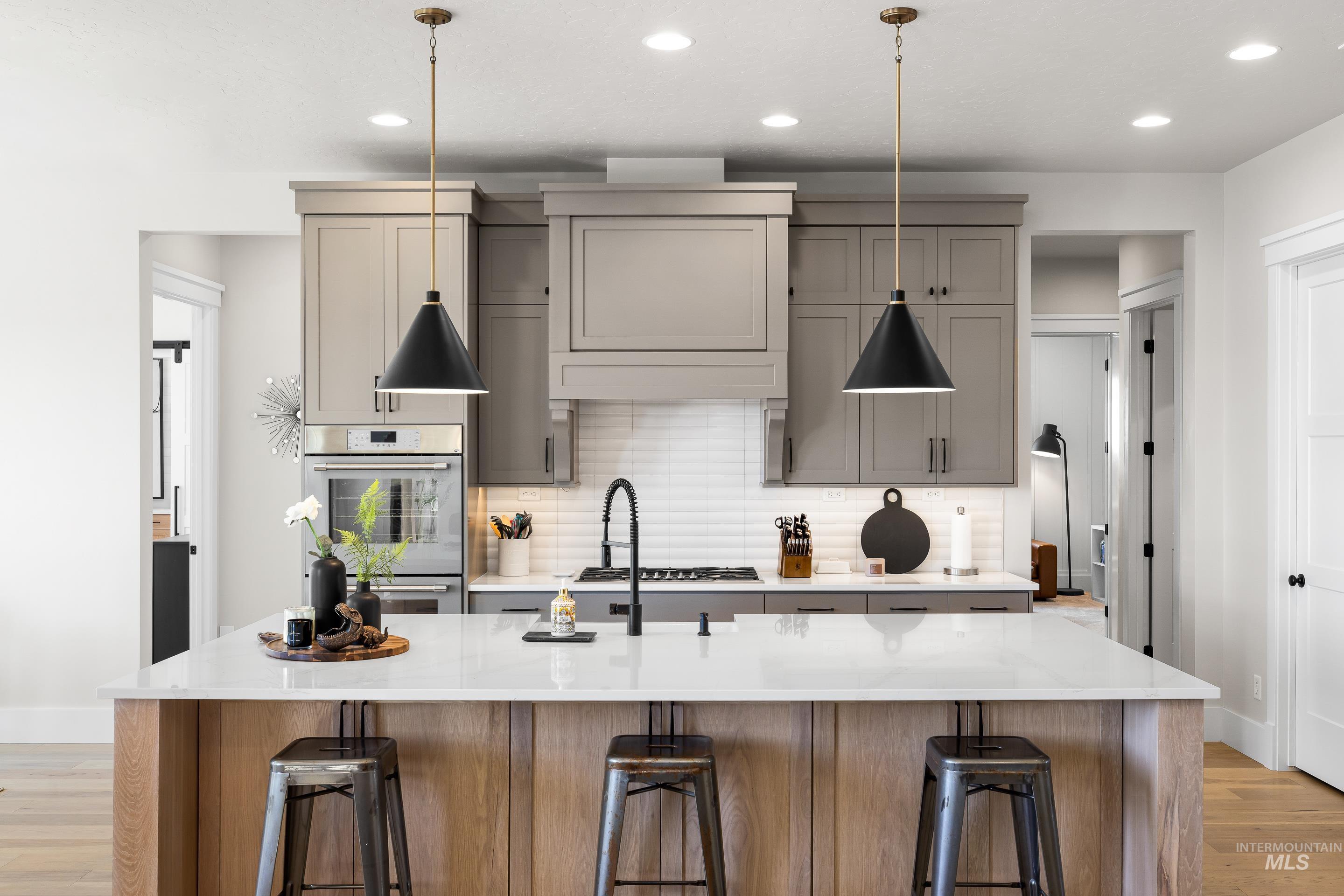 Kitchen with light wood-type flooring, tasteful backsplash, recessed lighting, and a kitchen island with sink