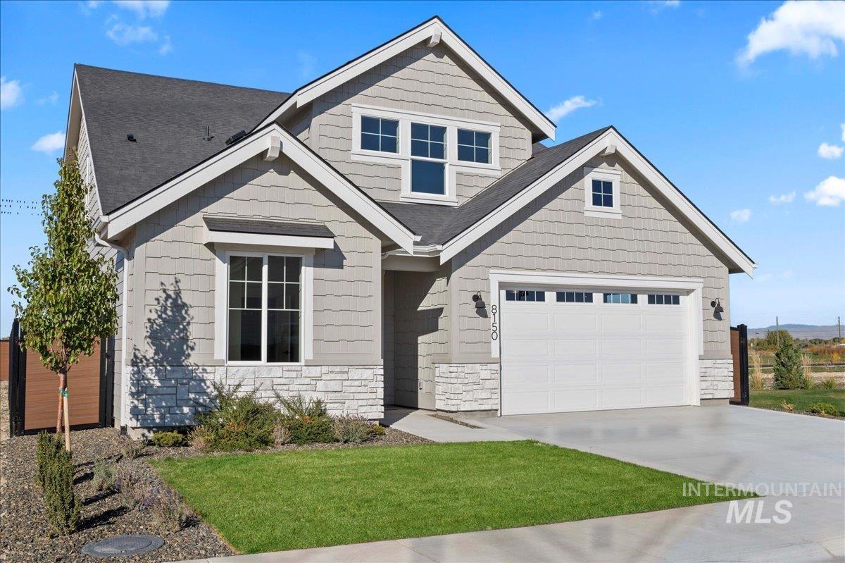 Craftsman house featuring driveway, stone siding, and a front yard