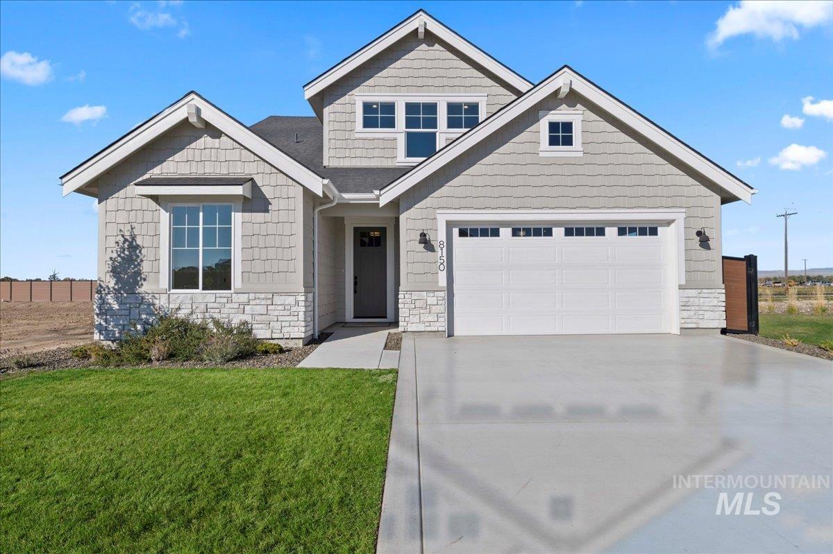 Craftsman-style house with stone siding, driveway, and a garage