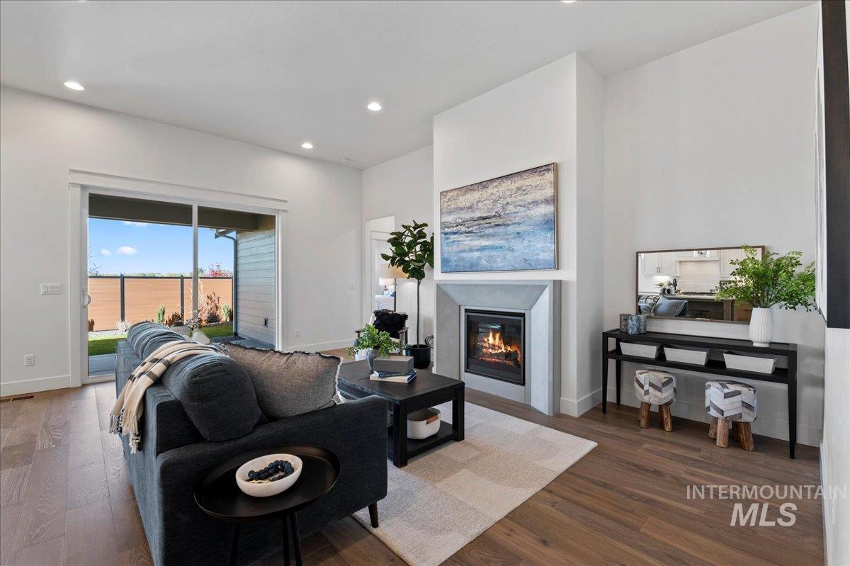 Living room featuring a glass covered fireplace, dark wood-style flooring, and recessed lighting
